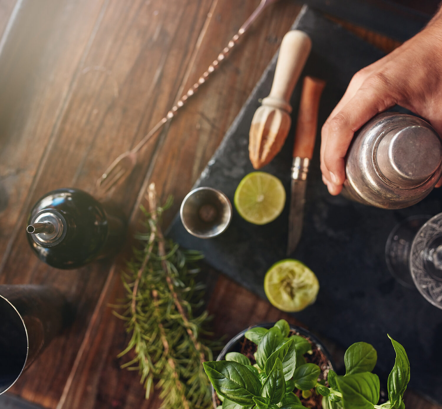 Top view shot of barman hand holding cocktail shaker on table with ingredients.